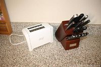 Overview of the knife set in wooden block and white Master Chef toaster placed on a granite countertop.
