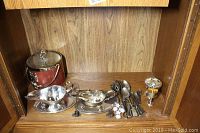 Photo showing vintage ice bucket, two silver sauce jugs with trays and ladle, serving spoons, tongs, and decorative goblet
