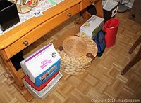Wide view showing the Igloo Little Playmate cooler, Coleman mini cooler, wicker picnic basket, and other picnic items under the wooden table.