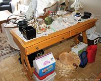 Full view of oak side table with various objects on top and underneath showing the table structure and finish.