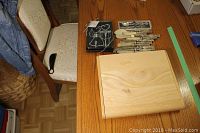 Photo of three boxed sets on a wood table including a wooden box with cheese knives, a canape knife set in original box, and a wooden wine opener box