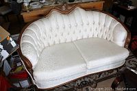 Full front view of the French Provincial style loveseat showing curved backrest, button tufting, and carved wood trim.