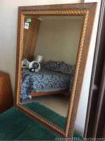 Front view of the mirror reflecting a bed and some furniture in a room.