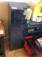 Side view of the sculpture plinth showing the dark marbled formica finish and the stepped cutout.