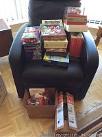 Lot contents of boxes stacked on a black chair including Christmas ornaments and Noma LED lights.