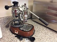Front left view of machine on countertop showing lever arm, boiler column and portafilter attached