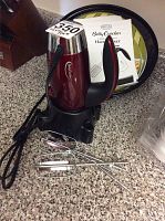 Betty Crocker red hand mixer with chrome top, two attached metal beaters, instruction manual, burner covers, and pie cover.