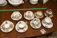 Photo showing eight assorted teacups and saucers displayed on a wooden table, including Princess Elizabeth Coronation set and Hammersley pieces.