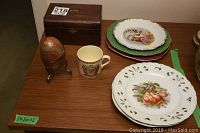 Overall view of the lot showing wooden antique tea box, decorative egg on stand, coronation cup, and five assorted decorative china plates stacked