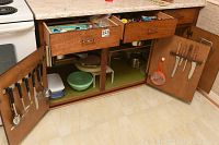 Open kitchen cabinet with two drawers and two cupboards showing various kitchenware inside