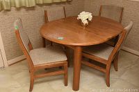 Full view of rectangular wooden kitchen table and four matching upholstered chairs, arranged around the table in a room corner.