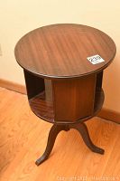 Front and top view of the round mahogany side table showing the revolving top with open compartments.