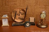 Two vintage desk clocks with additional desk accessories placed on a wooden surface against cork-board background
