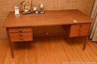 Front view of full teak veneer desk showing wide rectangular top, four legs, and two drawer units with square handles.