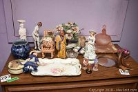 Overall collection of china figurines, a floral ceramic tray, glassware, and an artisan wall mirror on a wooden dresser surface