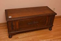 Full front view of cedar lined mahogany blanket chest showing carved front panel, rope twist columns, bun feet.