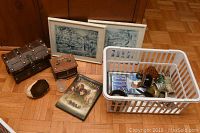 Full overview of lot showing wooden chests, framed artwork, Lord of the Rings DVD, and white basket with assorted items.
