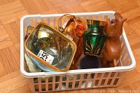 Basket containing various art glass items, a wooden squirrel figurine, and a brass-framed glass object with mineral slices inside.