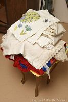 Stack of wool Afghan blankets with vibrant colors and a pillow on top, placed on a small plastic decorator table.