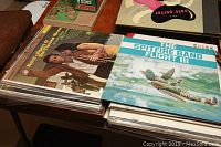 Photo showing stacks of vinyl records and a Eaton's catalog with identifiable album covers including The Spitfire Band Flight III and Herb Alpert & The Tijuana Brass Whipped Cream & Other Delights.
