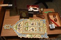 Photo shows table with sterling silver frame, wood and metal book ends, letter opener, hand-painted wood decor piece, wooden baby shoe form, metal aperitif glass, lighter, ashtray, and a wood box with eggs and pen.