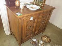 Full view of the oak sideboard showing the front with drawer and two lattice patterned doors. Several items rest on top excluding contents from sale.