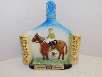 Front view of the collectible Jim Beam decanter showing the blue top, jockey on horse figure, and side text.