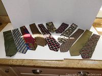 Image showing ten men's silk ties laid out in a row, showcasing different colors and patterns on a white background.