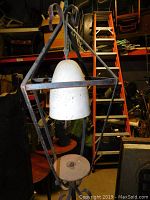 Close-up view of the lantern style metal bell stand showing the white bell inside the geometric frame and circular platform below.