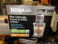 Front and side of the unopened box showing NINJA Ultra Prep Ultimate Food & Drink Maker with 3 blades and power pod, highlighting features like total crushing, power chopping, nutrient extraction, and dough mixing.