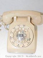 Front view of beige retro rotary dial phone showing dial with numbers and letters.