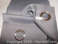 Close up photo of folded gray drape panel showing silver metal grommets at top edge.