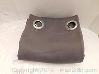 Folded gray window drape showing metal grommets at top edge