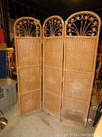Full view of the three-panel wicker room divider showing woven pattern and decorative arched tops.