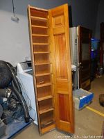 Tall wooden pantry cabinet standing upright with door opened wide showing multiple narrow shelves inside. Cabinet measures approx. 81 inches tall, 14 inches wide, and 4 inches deep.