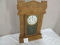 Front view of the solid oak gingerbread mantel clock showing the intricate carved details and the glass door with decorative decal.