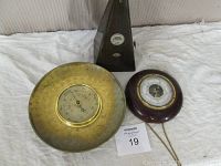 Photo of the metronome and two barometers on a white surface showing overall lot condition and sizes.