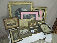 Overall arrangement of eleven assorted antique prints with various frame styles and sizes, displayed on white surface.