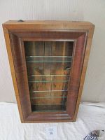 Front view of the antique OG shelf clock showing mahogany veneer frame and glass shelves inside.