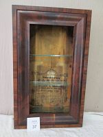Front view of the antique OG shelf clock showing rosewood veneered frame, glass door, three glass shelves, and printed interior panel.