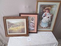 Three framed art prints displayed on a white cloth with one large and two smaller frames.