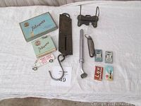 Photo showing Players cigarette packs, metal air gauge, paper holder, folding scissors, knife, razor blade packs and other small items.