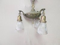 Front angled view of the 3-light brass fixture showing the ribbed glass shades and ornate brass mounts.