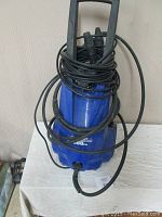 Front view of blue Simoniz electric pressure washer with coiled power cord and hose.
