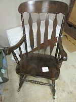 Front view of the solid maple rocking chair showing the curved top backrest and spindled back with curved armrests.