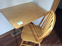 Wall-mounted desk and matching wooden chair seen from an angle showing desk surface and chair seating area