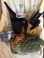 Photo showing oven mitt, black gardening watering pitcher, glass jar, Hershey Chicago collectible tin, wood knife block with knives, scissors, and extension cord