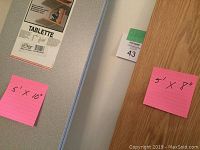 Close-up of shelf surfaces showing gray and wood-toned finishes with pink measurement notes.