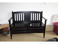 Front view of the black wood storage bench showing slatted back and drawers in base.