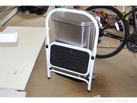 Full view of folding step stool with white frame and black steps.